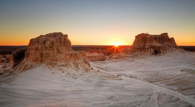 Sunset on the far horizon through raised desert formations at Mungo National Park in Australia