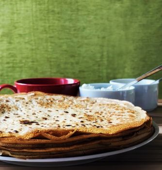 food Pancakes with local bee honey white cheese and tea and spoons on a green background