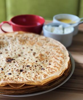 food Pancakes with local bee honey white cheese and tea and spoons on the background on focus