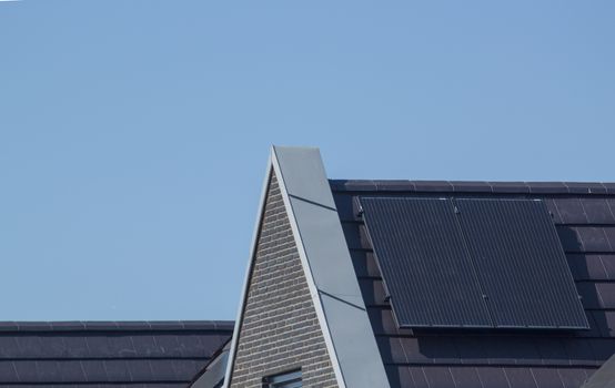 Solar panels on the roof of a house against a clear blue sky