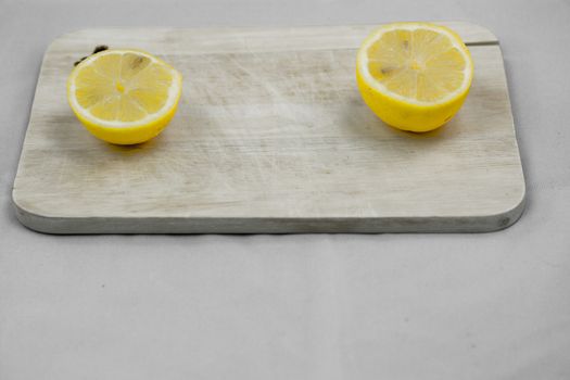 two lemons on a wooden board white backround
