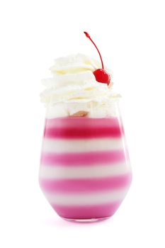 Pink striped jello dessert in glass with whipped cream and red candied cherry on top isolated on white background