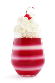 Red striped jello dessert in glass with whipped cream and red candied cherry on top isolated on white background