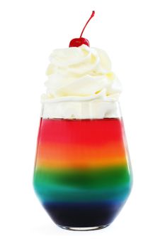 Rainbow colored jello dessert in glass with whipped cream and red candied cherry on top isolated on white background