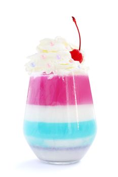 Striped jello dessert in glass with whipped cream and red candied cherry on top isolated on white background
