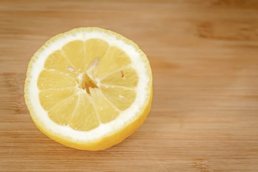 Half of a lemon with a bone on a light wooden board