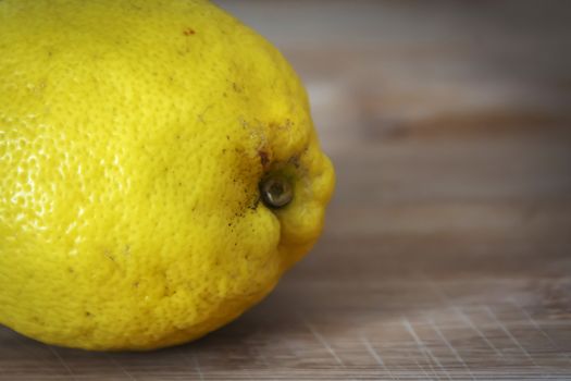 Close up shot of a delicious, juicy lemon on a wooden cutting board ready to be sliced and eaten