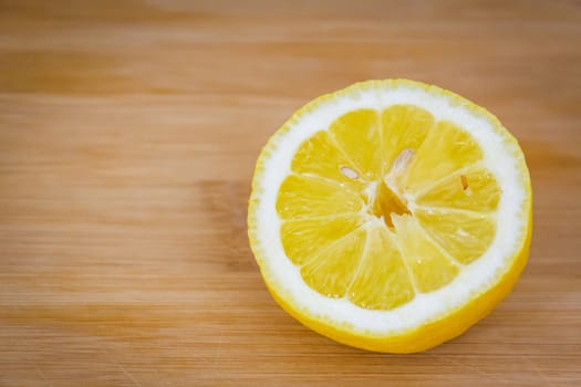 Half of a lemon with a bone on a light wooden board