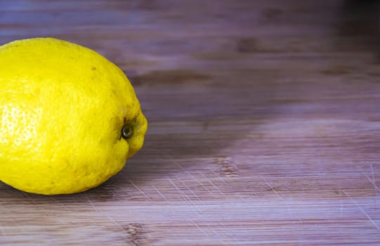 Close up shot of a delicious, juicy lemon on a wooden cutting board ready to be sliced and eaten