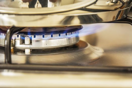 Focus of blue flame gas on a cooker boiling pot in kitchen gas stove. Cooking Food.