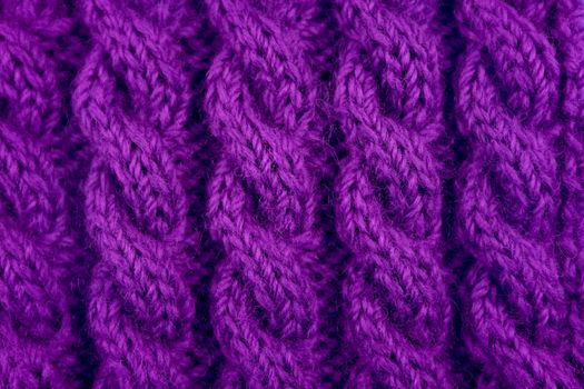 Detail of purple handknit coiled rope cable knitting stitch as abstract background