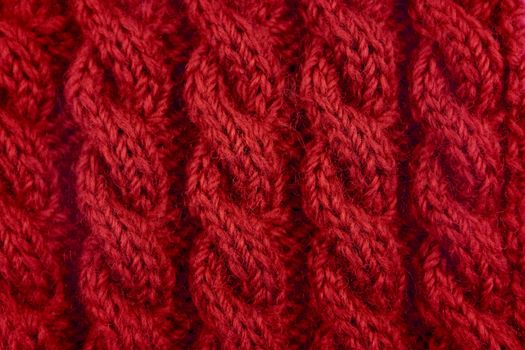 Detail of red handknit coiled rope cable knitting stitch as abstract background