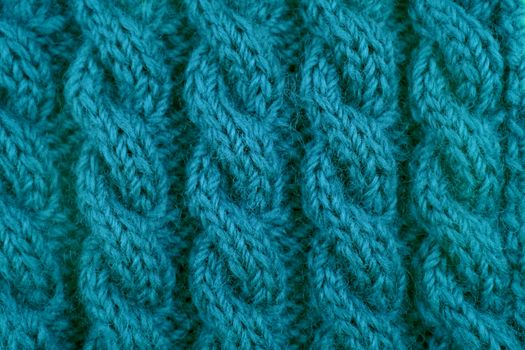 Detail of teal handknit coiled rope cable knitting stitch as abstract background