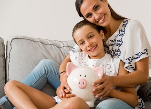 Mother and daughter with a piggy bank for her future savings