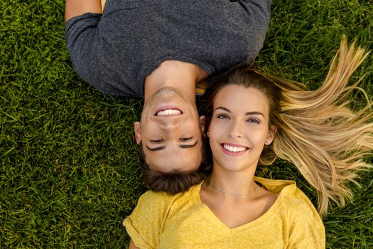 Portrait of a young beautiful couple lying on the grass