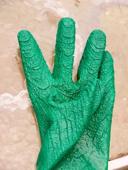 a wet single green gloves on glass table; Essex; UK
