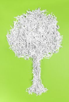 Tree made of shredded paper, on bright green background. Recycling and environment protection concept.