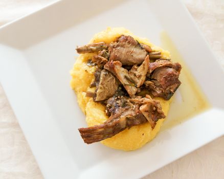 Typical italian food,polenta with Capretto( small goat meat) roasted, view from above.