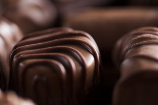 Chocolate bars and pralines on wooden background