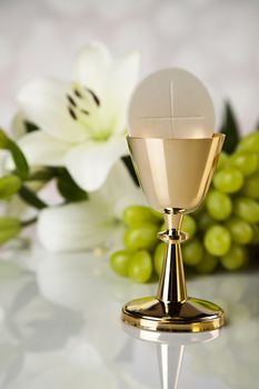 Holy communion a golden chalice with grapes and bread wafers