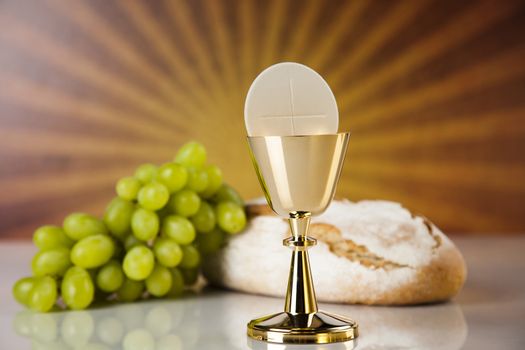 Holy communion a golden chalice with grapes and bread wafers