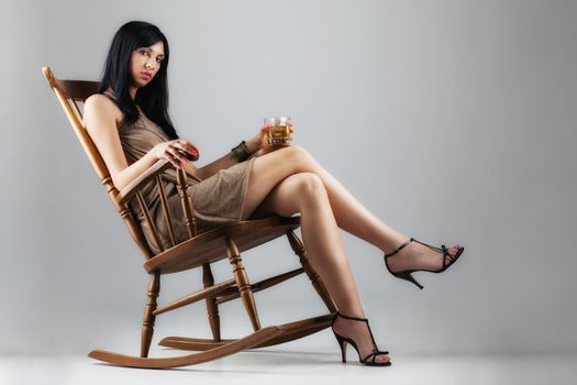 elegant girl with whiskey on a vintage rocking chair