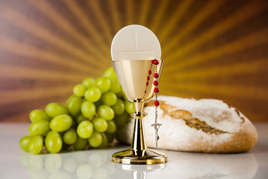 Holy communion a golden chalice with grapes and bread wafers