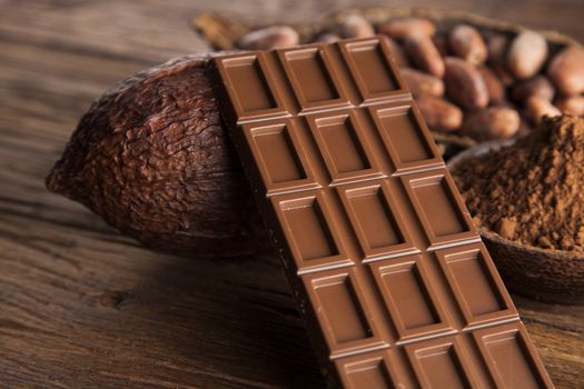 Dark homemade chocolate and cocoa pod on wooden