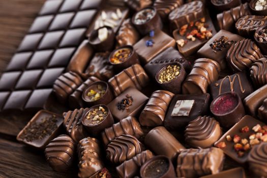 Chocolate bars and pralines on wooden background