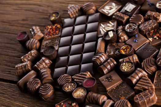 Chocolate bars and pralines on wooden background