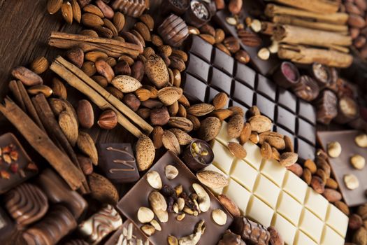 Chocolate bars and pralines on wooden background