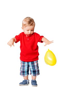 baby boy standing on the floor with a yellow balloon