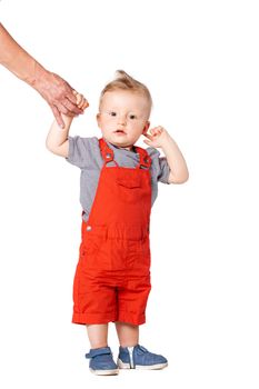 baby boy standing on the floor and holding an adult hand