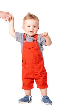 baby boy standing on the floor and holding an adult hand