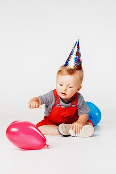 baby boy with birthday hat and balloons