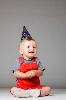 baby boy with birthday hat in overall red shorts