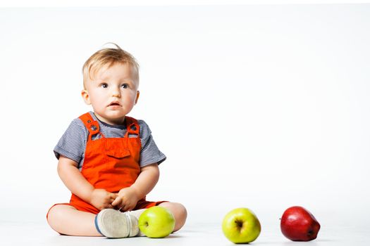 baby boy playing with green and red apples