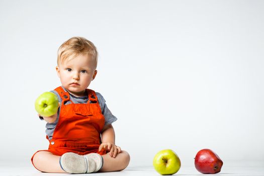 baby boy playing with green and red apples