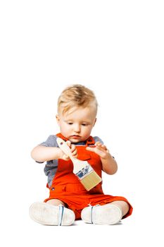 baby boy sitting on the floor, holding paint brush, isolated on white