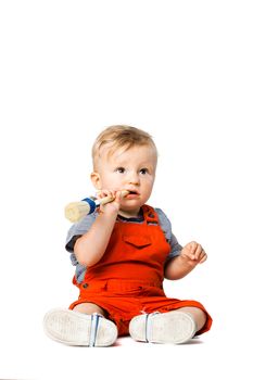 baby boy sitting on the floor, holding paint brush, isolated on white