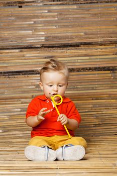 baby boy sitting on the floor, holding a pencil, on bamboo background