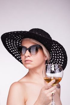 silhouette portrait of a caucasian girl with short hair, hat and glasses, holding wine