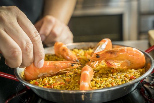 Chef is adding seafood to paella, close up