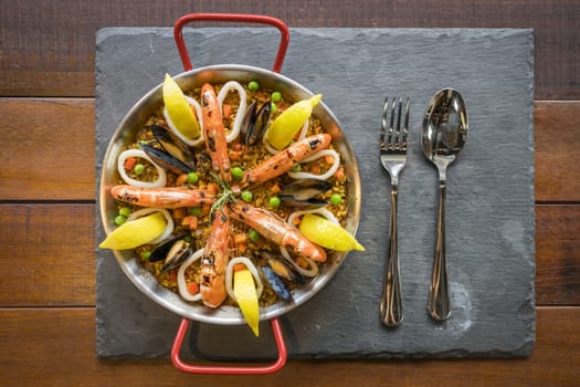 Paella with seafood vegetables and saffron served in the traditional pan top view.
