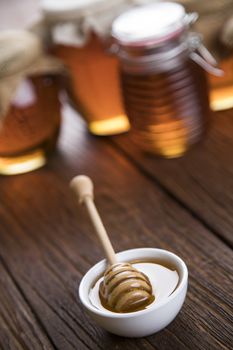 Honey in jar with honey dipper on wooden background