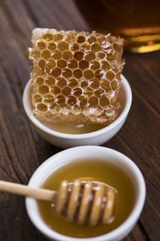 Honey in the comb, glass jar on wooden background