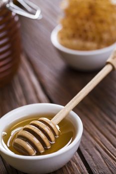 Honey in the comb, glass jar on wooden background