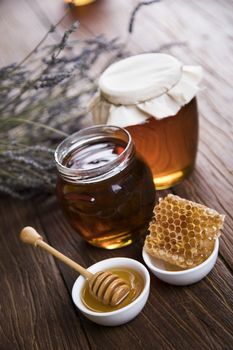 Honey in the comb, glass jar on wooden background