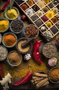 A selection of various colorful spices on a wooden table in bowls