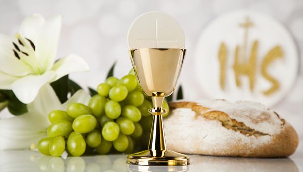 Holy communion a golden chalice with grapes and bread wafers